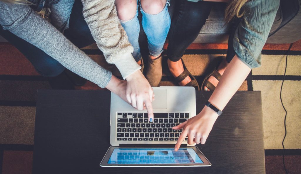 Hände deuten auf Laptop