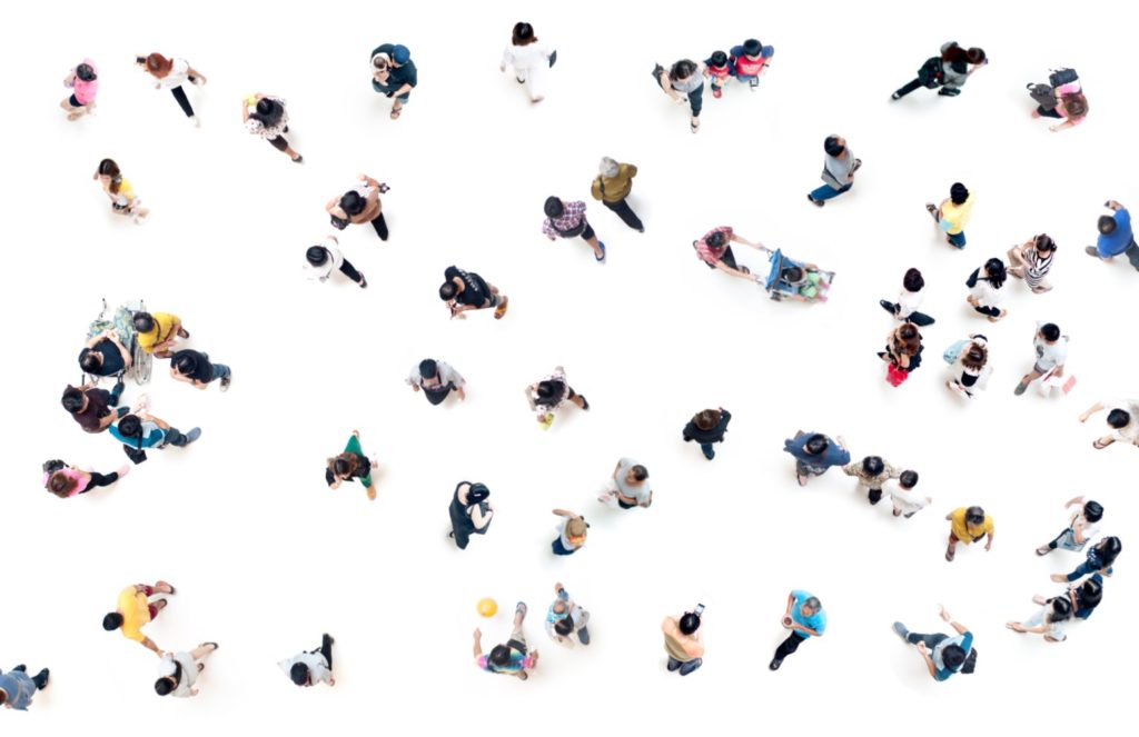 Foto aus Vogelperspektive auf Menschen, die vor weißem Boden in kleinen Grüppchen stehen