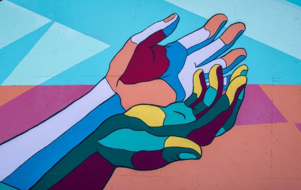 Streetart. Zwei farbige Hände umfassen sich.