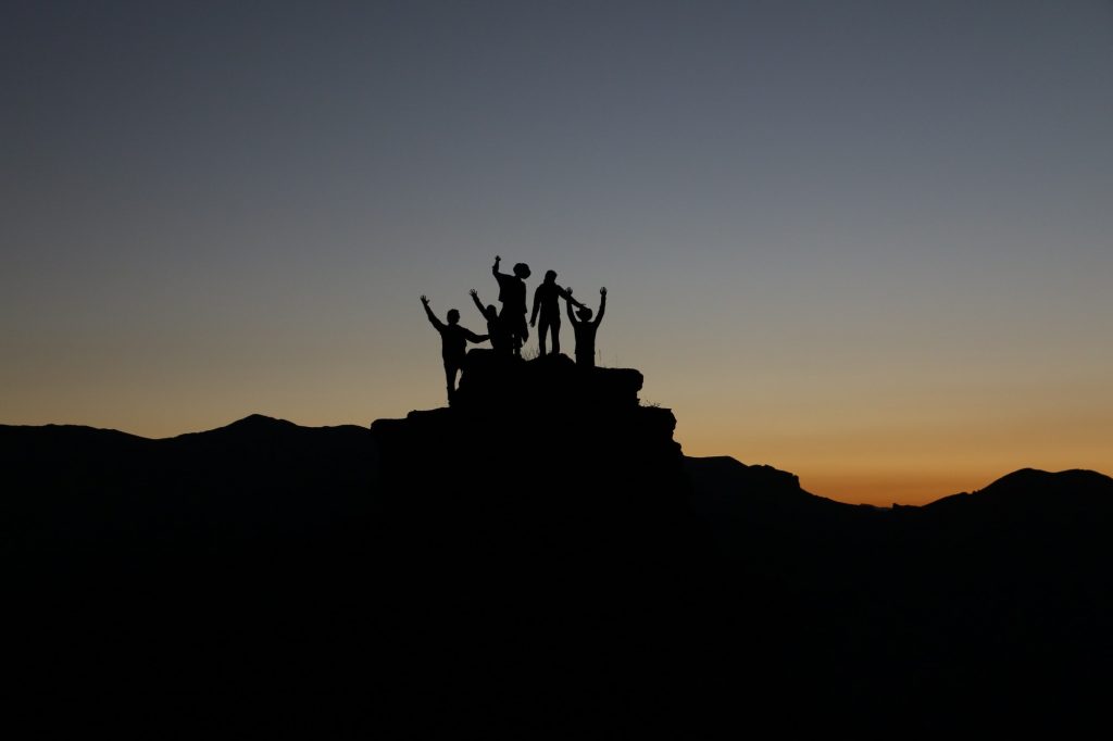 Foto von einer Gruppe von Menschen, die auf einer Hügelspitze stehen.